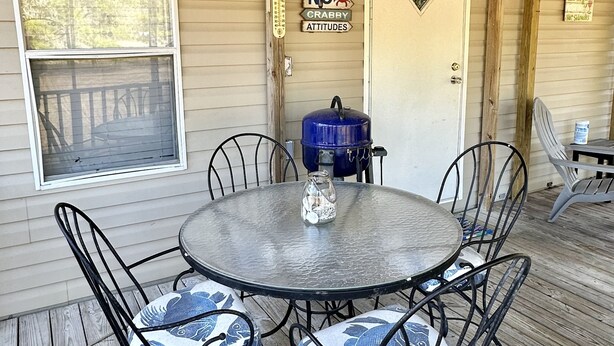 A covered outdoor patio with a round table and chairs, a ceiling fan, and a blue water cooler.