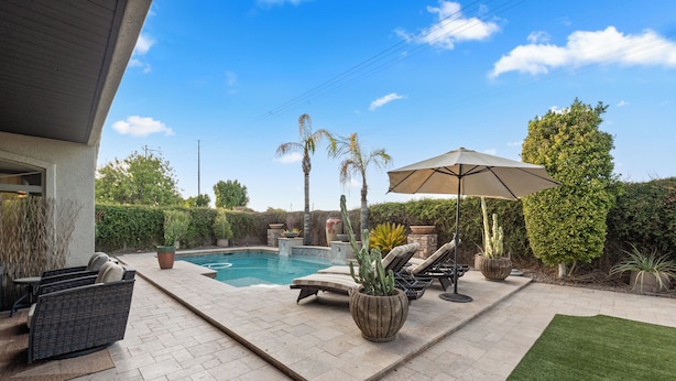 A backyard with a swimming pool, lounge chairs, and a patio umbrella. - PRIVATE RESORT RETREAT - Pool, Hot Tub, Sauna & Games (Gilbert)
