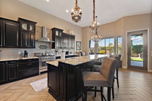 A spacious kitchen with dark cabinetry, a central island, and a chandelier. - PRIVATE RESORT RETREAT - Pool, Hot Tub, Sauna & Games (Gilbert)