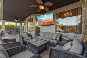 A covered outdoor seating area with wicker furniture, a flat-screen TV, and a ceiling fan. - PRIVATE GILBERT RETREAT - Pool, Hot Tub, Sauna & Games (Gilbert)