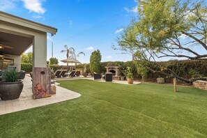A backyard with a patio, outdoor furniture, a stone fireplace, and a well-maintained lawn. - PRIVATE RESORT RETREAT - Pool, Hot Tub, Sauna & Games (Gilbert)