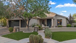 A residential house with a garage, a well-maintained lawn, and a variety of landscaping including shrubs and a tree. - PRIVATE RESORT RETREAT - Pool, Hot Tub, Sauna & Games (Gilbert)