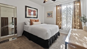 A bedroom with a bed, a ceiling fan, a large mirror, and two framed pictures on the wall. - PRIVATE RESORT RETREAT - Pool, Hot Tub, Sauna & Games (Gilbert)