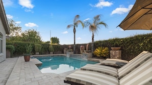 A swimming pool with lounge chairs and a stone wall. - PRIVATE RESORT RETREAT - Pool, Hot Tub, Sauna & Games (Gilbert)