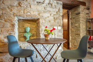 Un muro in pietra con una porta di legno, un tavolino con un vaso di fiori e due sedie moderne.