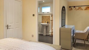 A bedroom with a bed, a desk, a chair, a wardrobe, and a bathroom visible through an open door. - Leven Lodge 1 - UK46042 (Loch Lomond)