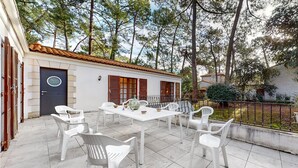 A patio with a table and chairs, a door, and a window with shutters.