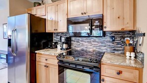 Une cuisine avec des meubles de rangement en bois, un réfrigérateur en acier inoxydable, une cuisinière noire et un four à micro-ondes.