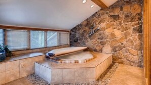 Un área de spa con pared de piedra, banco de madera y ventana con persianas.