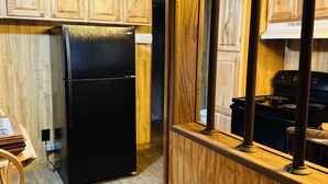 Una cocina con armarios de madera, un refrigerador negro y una estufa.