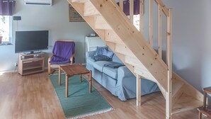 A living room with a wooden staircase, a television, a sofa, and a chair. - 1 bedroom awesome home in Ljungbyhed (Ljungbyhed)