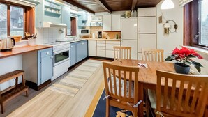 A kitchen with white cabinets, a stove, and a dining area with wooden chairs and a table. - 1 bedroom awesome home in Ljungbyhed (Ljungbyhed)