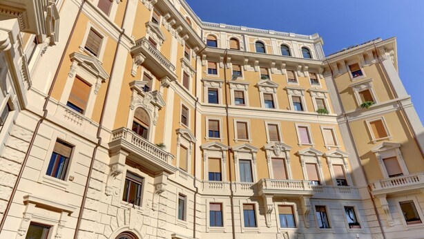 Um edifício de vários andares com arquitetura clássica, com varandas e grandes janelas.