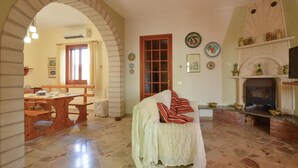A cozy living room with a fireplace, a dining area with a wooden table, and a cozy chair. - 3 bedroom lovely home in San Giorgio (San Giorgio)