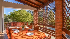 An outdoor dining area with a table set for four, surrounded by wooden chairs and a brick pillar. - 3 bedroom lovely home in San Giorgio (San Giorgio)
