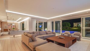A modern living room with a sectional sofa, a coffee table, and a dining area with a glass table. - Beach front home in Savudrija (Savudrija)