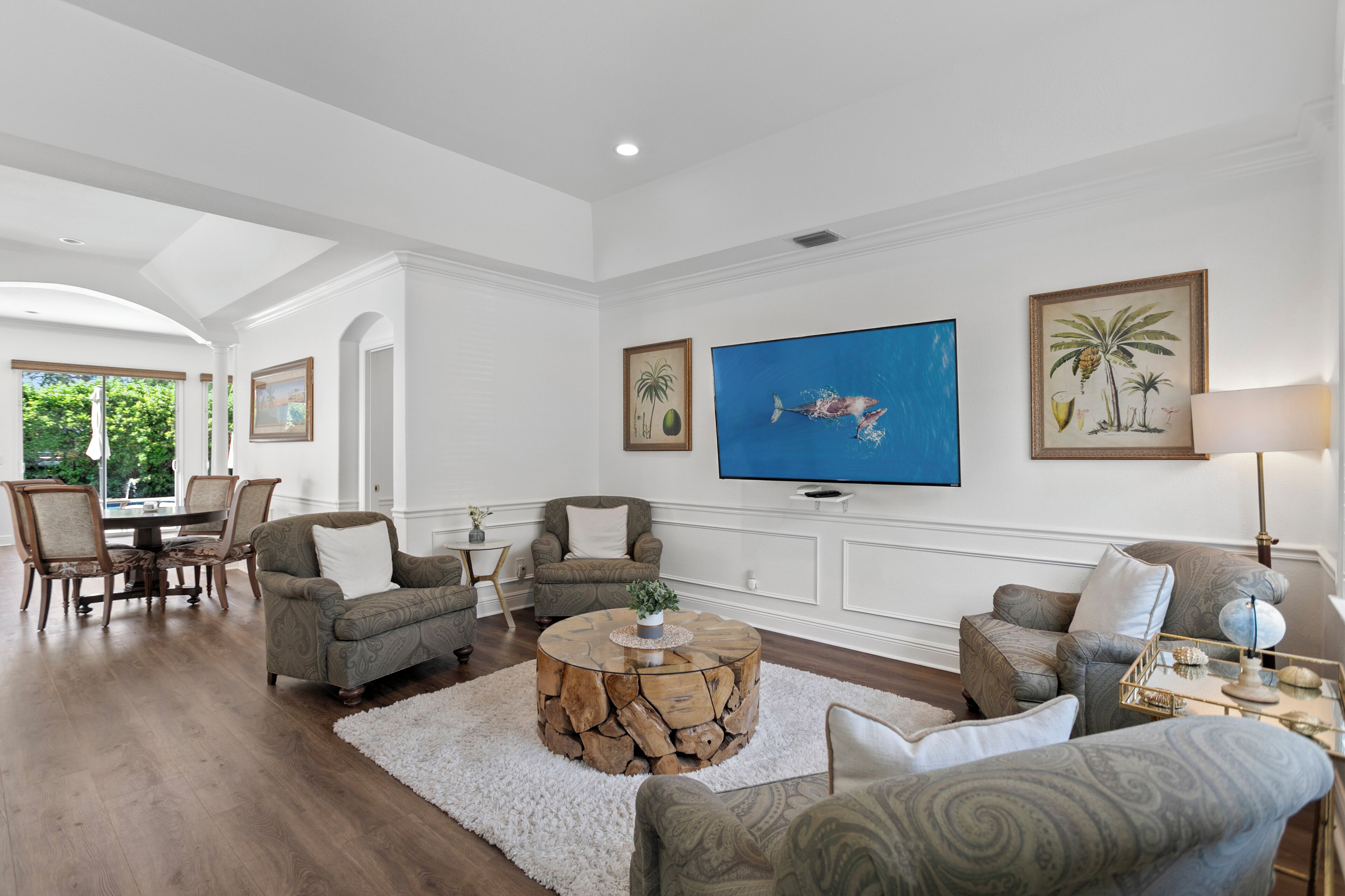 A spacious living room with a large flat-screen TV, comfortable seating, and a dining area with a table and chairs.