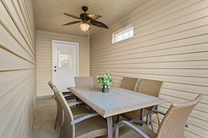 A dining area with a table and chairs, a ceiling fan, and a door.