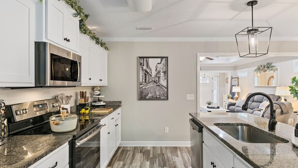 A modern kitchen with white cabinets, stainless steel appliances, and a large island.