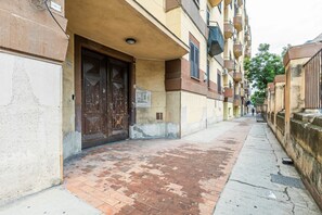 Een smalle straat met een gebouw dat een grote houten deur en een klein bord heeft.