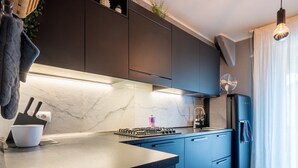 Eine moderne Küche mit dunklen Schränken, einer Marmor-Spritzschutzleiste, einem Gasherd und einem eingebauten Backofen.
