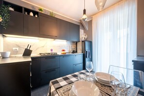 Una cucina moderna con mobili scuri, un piano di lavoro in marmo e una zona pranzo con tovaglia a quadri.