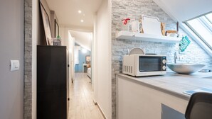 A modern kitchen with a microwave, a bowl, and a shelf with kitchen items. - Comfortable attic located on the third and last floor of a building without a lift.It comfortably accommodates two people in 40 m2 of space with a double bedroom.Small building with a green space and ample free parking in front of the house, near the cen (Parma)
