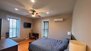A bedroom with a bed, a desk, a chair, a television, and a ceiling fan. - Full House booking of a history building close to the Dunes (Chesterton)