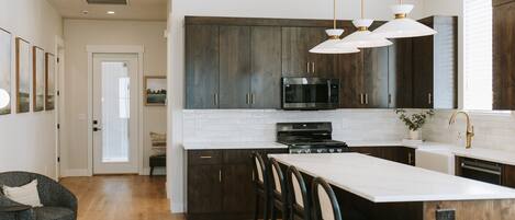 A modern kitchen with dark wood cabinets, a white countertop, and a central island with bar stools.