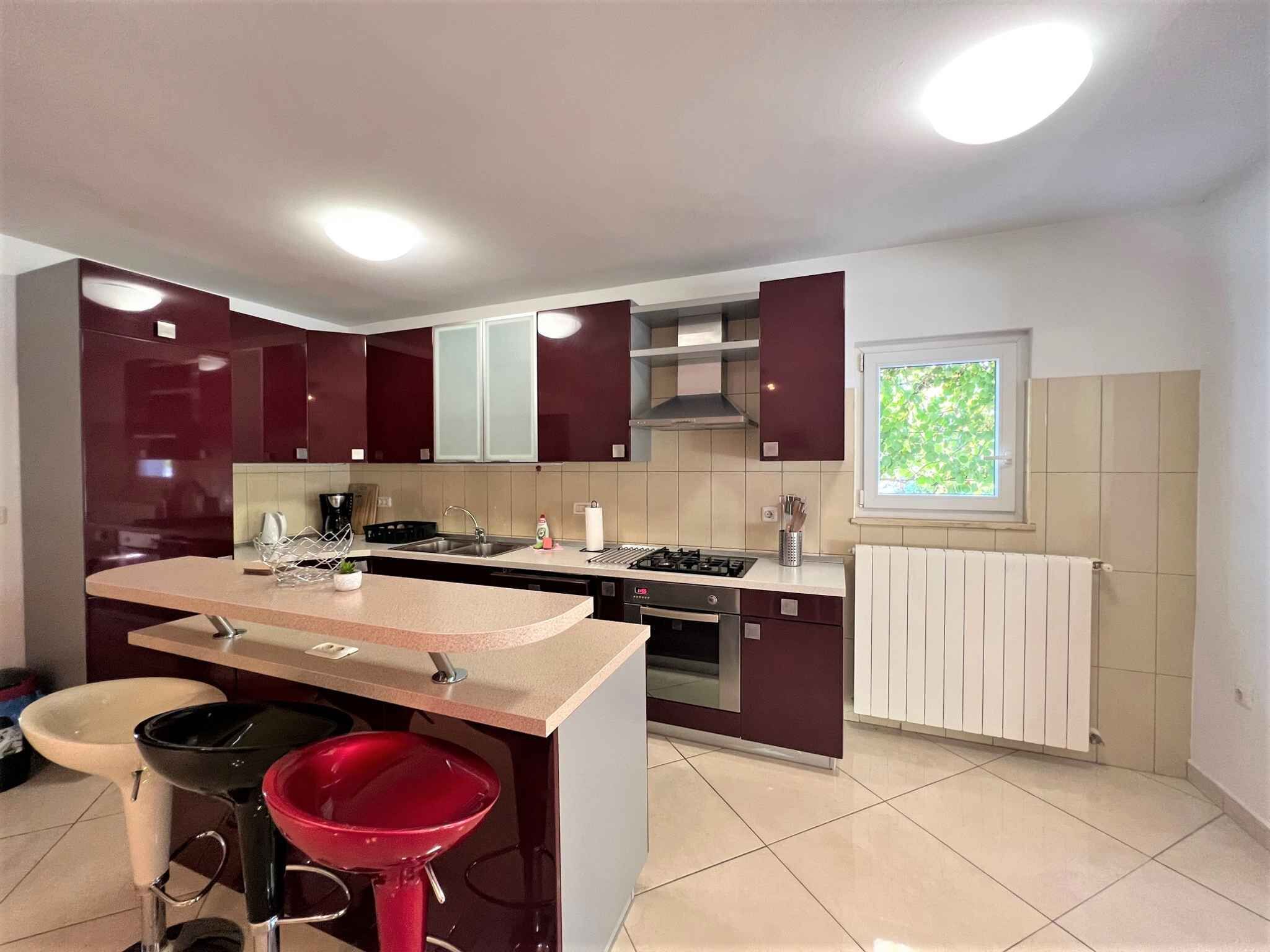 Una cucina moderna con isola centrale, forno integrato e una finestra che permette l'illuminazione naturale.