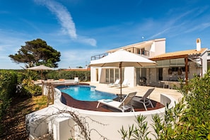 A modern house with a swimming pool, outdoor furniture, and a large umbrella. - Villa Estrella - Canutells (Es Canutells)