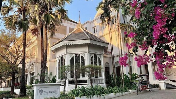 A traditional-style building with a central pavilion, surrounded by palm trees and bougainvillea. - Ping Nakara Boutique Hotel and Spa (Chiang Mai)