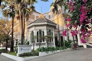 Un edificio de estilo tradicional con un pabellón central, rodeado de palmeras y buganvillas.