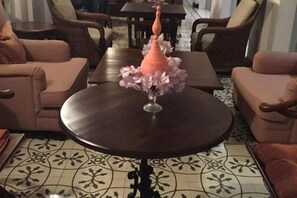 Une table ronde surmontée d’un vase de fleurs, entourée de deux canapés et posée sur un sol à motifs.