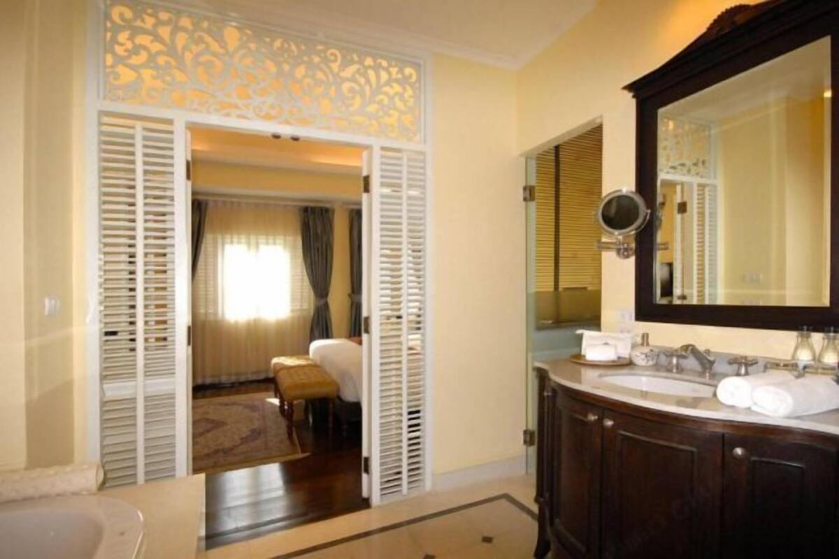 Un baño con un espejo grande, dos lavamanos y una bañera.