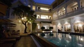 A multi-story hotel with a swimming pool, outdoor seating, and a tree. - Ping Nakara Boutique Hotel and Spa (Chiang Mai)