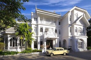 Un grand bâtiment blanc avec de nombreuses fenêtres et une voiture garée devant.