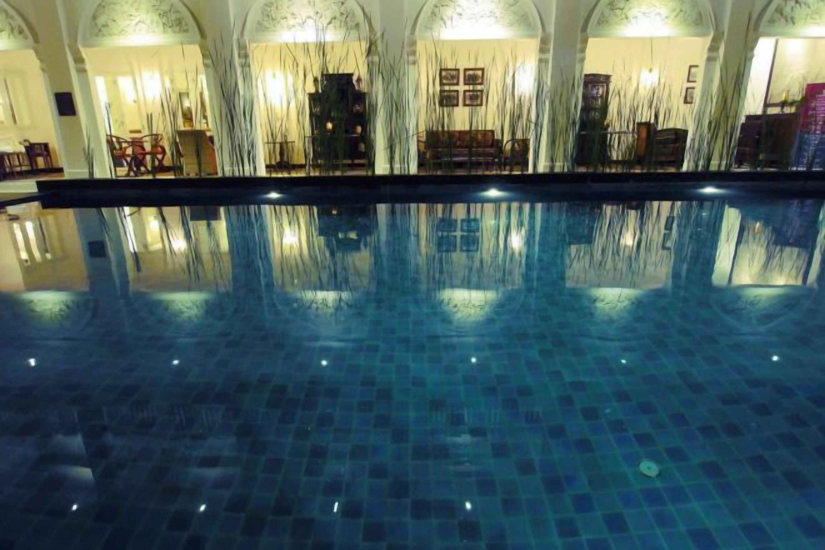 A swimming pool with a tiled floor and a reflection of the room's interior.