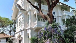 A multi-story building with balconies and a large tree with purple flowers in front. - Ping Nakara Boutique Hotel and Spa (Chiang Mai)