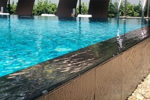 Una piscina con agua cristalina, un borde de piscina oscuro y un borde de piedra.
