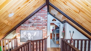 Un intérieur en bois avec un mur en briques, un plafond en bois et un escalier.