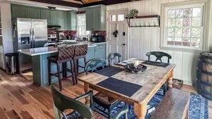 Une cuisine spacieuse dotée de meubles en bois, d’un grand îlot central et d’un coin repas avec une table et des chaises en bois.