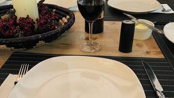 Uma mesa posta com um prato branco, um copo de vinho tinto, uma vela e uma garrafa de vinho.