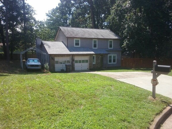 A two-story house with a garage, a covered carport, and a well-maintained lawn.