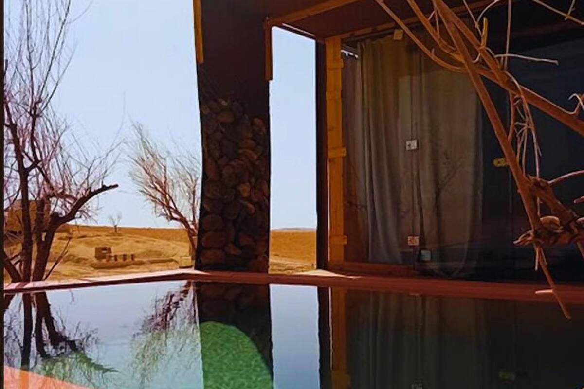 A modern building with a glass-enclosed pool, wooden deck, and a stone wall.