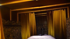 A room with a bed, stone walls, and a stone fireplace. - Revolution Stone Cliff Eco Resort  (Agafay)