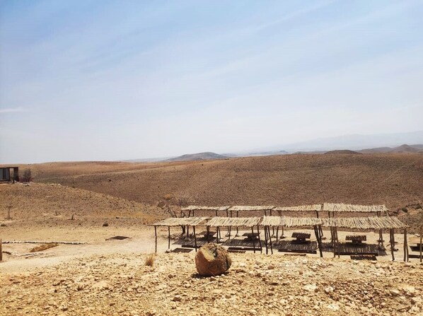 A desert landscape with a series of thatched-roof structures, possibly a traditional dwelling or guesthouse.