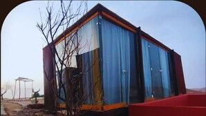 A modern, single-story building with large glass windows and a red exterior wall. - Revolution Stone Cliff Eco Resort  (Agafay)