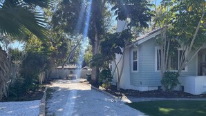 A gravel driveway leading to a house with a white exterior and a small front yard.