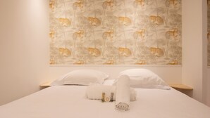 A neatly made bed with white linens, a rolled towel, and two small bottles on the bed. - Charming studio in Versailles - Welkeys (Versailles)